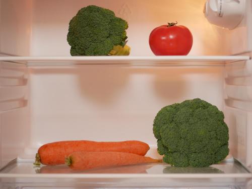 two shelves of a refrigerator with broccoli and an apple at Altavista mountain apartment in Samokov