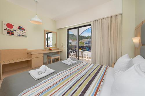 a bedroom with a bed and a desk and a window at Sunny Days Hotel in Ixia