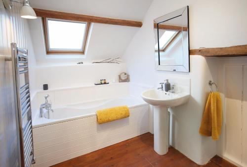 a bathroom with a tub and a sink and a mirror at Seekings Cottage in Knowstone