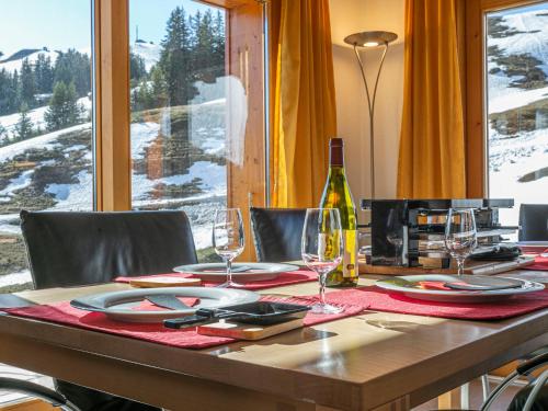 a wooden table with glasses and a bottle of wine at Chalet Martens by Interhome in Les Crosets