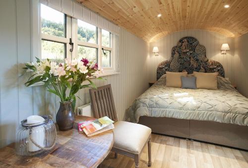 a bedroom with a bed and a table with flowers at Anne's Hut Monmouthshire 