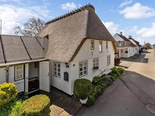 une maison blanche avec un toit de chaume dans l'établissement Holiday Home Gyril - all inclusive - 100m from the sea by Interhome, à Sønderby