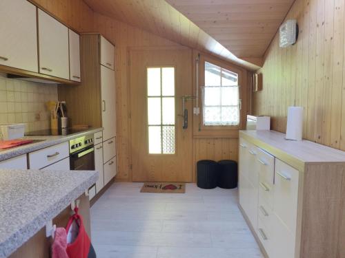 a kitchen with wooden walls and white cabinets at Apartment Chalet Vamika by Interhome in Niederried