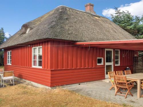 een rood huis met een rieten dak en een tafel bij Holiday Home Jorid - 300m from the sea in Western Jutland by Interhome in Vejers Strand