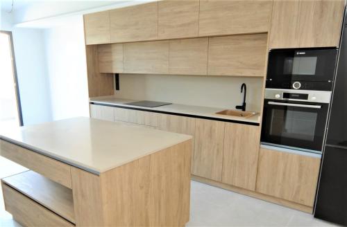 a kitchen with wooden cabinets and a black refrigerator at ATICO BOHIO premium in Benicàssim
