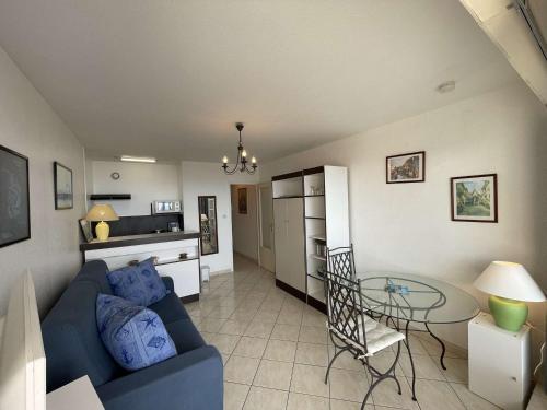 un salon avec un canapé bleu et une table dans l'établissement Studio à St-Jean-de-Monts avec parking et balcon fermé - FR-1-224C-212, à Saint-Jean-de-Monts
