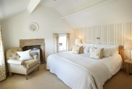 a white bedroom with a large bed and a chair at Winsmore Cottage in Bakewell