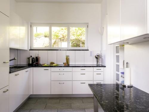 a white kitchen with white cabinets and a window at Holiday Home Carina Lakeview by Interhome in Carona