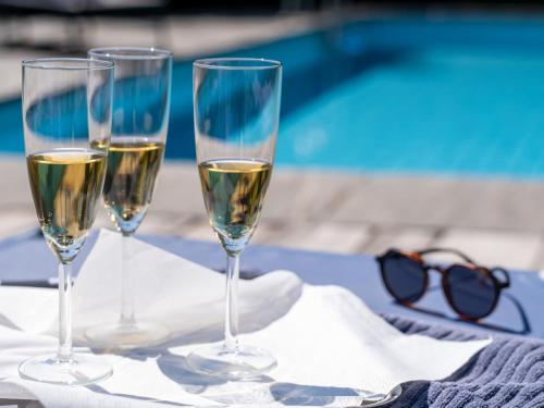 three glasses of white wine sitting on a table at Holiday Home Carina Lakeview by Interhome in Carona