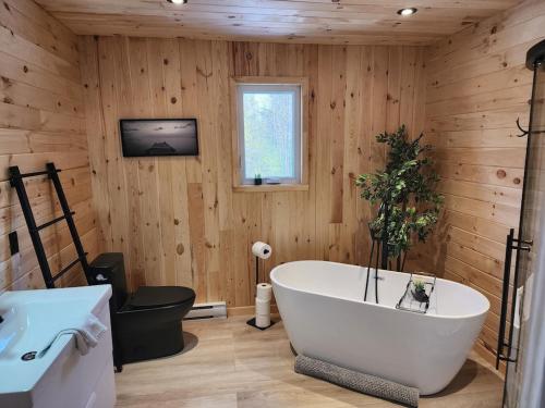 uma casa de banho com uma banheira branca numa parede de madeira em Spa calme au sommet em Saint Come