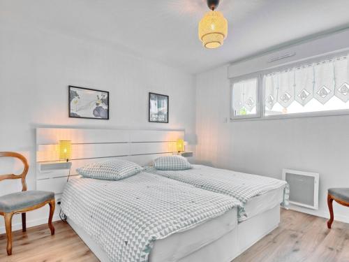 a white bedroom with a bed and a chair at Holiday Home la k'bane sur mer by Interhome in Étables-sur-Mer