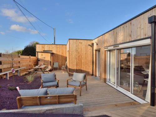 a wooden deck with two chairs and a couch at Holiday Home la k'bane sur mer by Interhome in Étables-sur-Mer