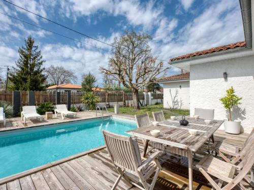 d'une terrasse avec une table et des chaises en bois à côté de la piscine. dans l'établissement Villa Andernos Bassin by Interhome, à Andernos-les-Bains