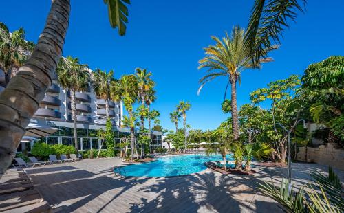 een zwembad met palmbomen en een gebouw bij Albir Playa Hotel & Spa in Albir