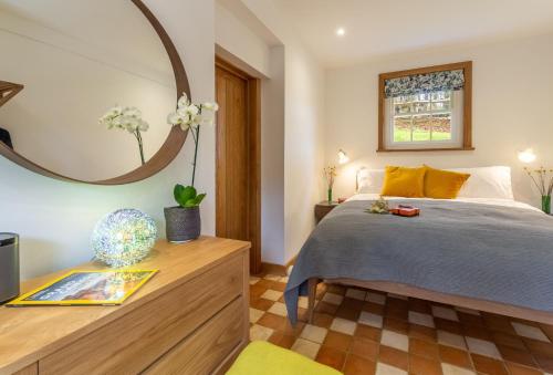 a bedroom with a bed and a mirror at Inkpen Cottage in Robertsbridge