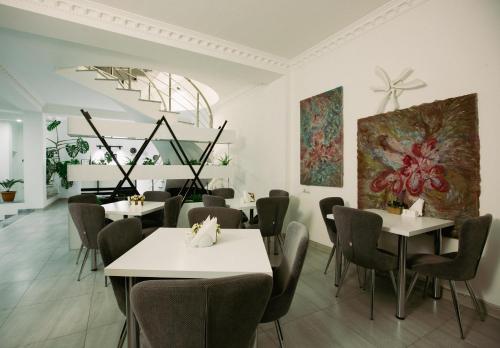 un restaurant avec des tables, des chaises et des peintures murales dans l'établissement White House, à Tbilissi