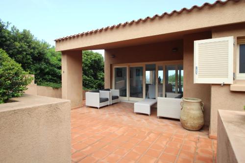 un patio con sillas blancas y una casa en VILLA ASFODELO-INFINITYHOLIDAYS, en Costa Paradiso