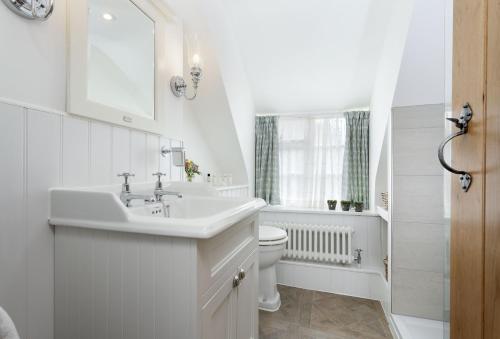 La salle de bains blanche est pourvue d'un lavabo et de toilettes. dans l'établissement Harrowby End, à Ebrington