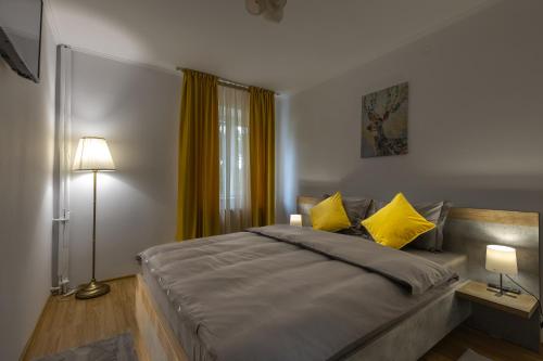 1 dormitorio con 1 cama grande con almohadas amarillas en Luxury 2 bedroom holiday apartment, en Piteşti