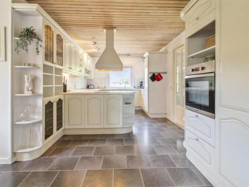 uma cozinha com armários brancos e um tecto de madeira em Holiday Home Aku - 24km from the sea in Western Jutland by Interhome em Højer