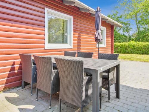 - une table avec des chaises et un parasol en face d'une maison dans l'établissement Holiday Home Aku - 24km from the sea in Western Jutland by Interhome, à Højer