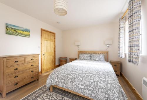 a bedroom with a bed and a wooden dresser at The Old Stables at Bradley's Farm in Holt