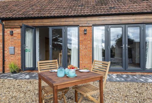 a wooden table and chairs in front of a house at The Old Stables at Bradley's Farm in Holt
