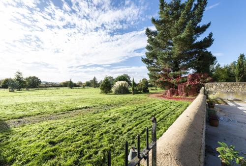 a field with a fence and a tree at The Old Stables at Bradley's Farm in Holt