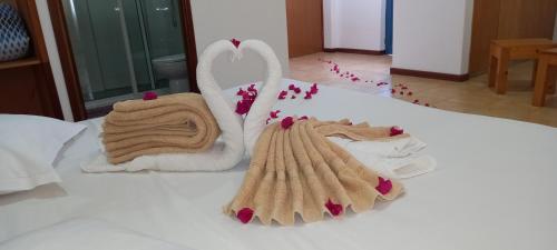 Una cama con toallas y una toalla con forma de corazón. en Txada Hostel, en Praia