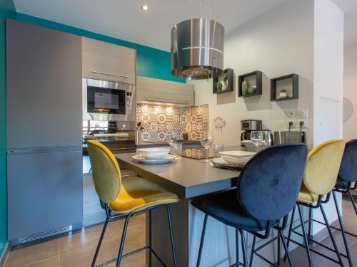 een keuken met een ontbijtbar met gele en blauwe stoelen bij Apartment Villa Marine by Interhome in Seignosse
