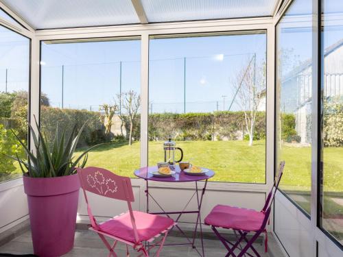 une table avec des chaises roses devant une fenêtre dans l'établissement Holiday Home Karome by Interhome, à Saint-Coulomb