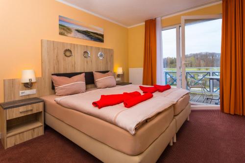 a bedroom with a large bed with red pillows on it at Appartementhäuser Achterwasserblick in Ostseebad Koserow