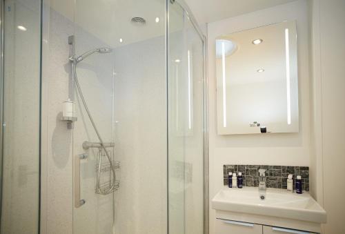 a bathroom with a shower and a sink and a mirror at Kirby Cottage in Harome
