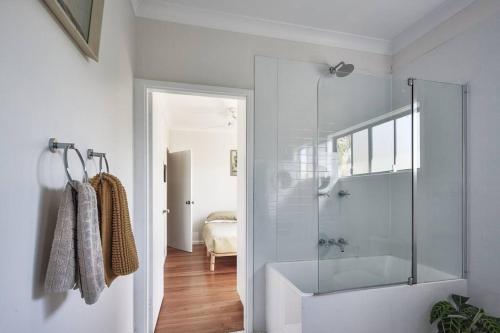 a bathroom with a glass shower and a bedroom at The Bakers Cottage - Crescent Head in Crescent Head
