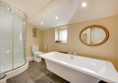 a bathroom with a tub and a toilet and a mirror at Harbour Masters House in Craster