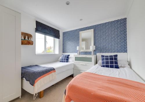 a bedroom with two beds and a mirror at Coastguard Cottage in Craster