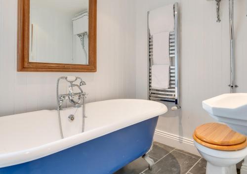 a bathroom with a tub and a toilet and a sink at Coastguard Cottage in Craster