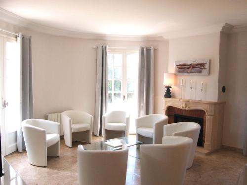 - un salon avec des chaises blanches, une table et une cheminée dans l'établissement Holiday Home La Villa by Interhome, à Saint-Jouan-des-Guérets