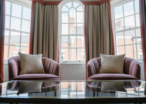 a living room with two chairs and a glass table at The Swan at Tarporley in Tarporley