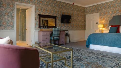 a bedroom with a bed and a table and a chair at The Swan at Tarporley in Tarporley
