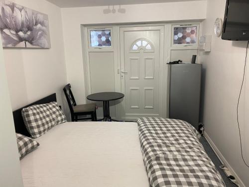 um quarto com uma cama, uma mesa e uma porta em Guest House in Milton Keynes em Milton Keynes