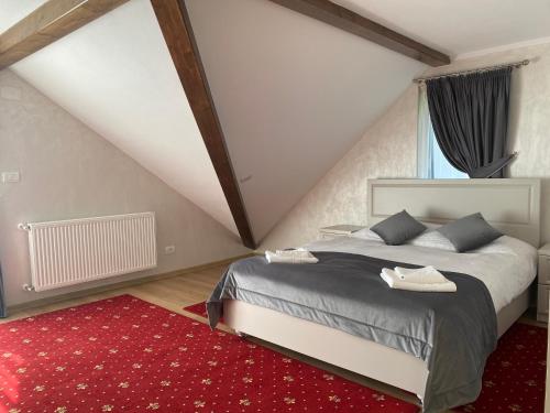 a bedroom with a bed and a red rug at CASA DE LA MUNTE in Frumosu
