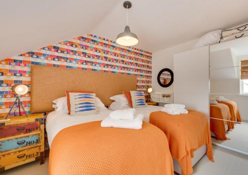 1 dormitorio con 2 camas con sábanas de color naranja en Salt Air - 9 Seafield, en Seahouses