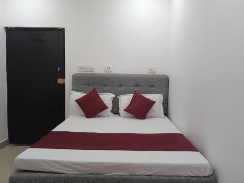 Schlafzimmer mit einem Bett mit roten und weißen Kissen in der Unterkunft Hotel Metro Regency in Lucknow