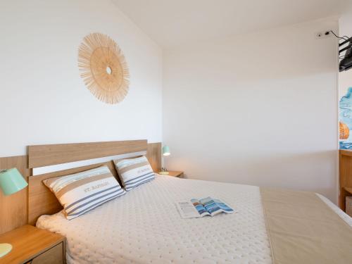 - une chambre blanche avec un lit et une tête de lit en bois dans l'établissement Studio Résidence Les Gemeaux by Interhome, à Saint-Raphaël