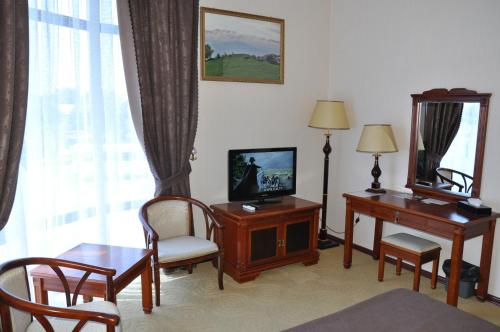 a living room with a television and a table and chairs at Firuz Hotel in Khujand