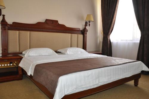 a bedroom with a large bed with a wooden headboard at Firuz Hotel in Khujand