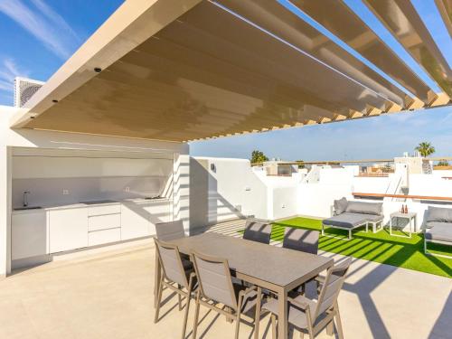 een patio met een tafel en stoelen op een dak bij Apartment Tropical Beach Penthouse by Interhome in Santiago de la Ribera