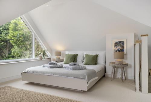 a white bedroom with a bed and a large window at Winacres Cottage in Nailsworth