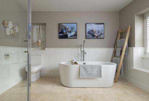 a white bathroom with a tub and a toilet at Winacres Cottage in Nailsworth